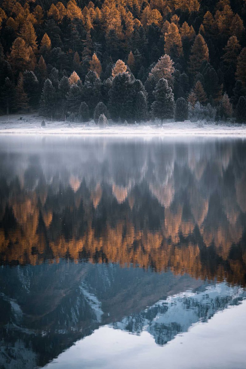 This is an image I took a while back but I love it because it shows the magic the change of season can bring. There is hoarfrost on the trees, the larch trees are in full color, fog is rising above the lake, and on the mountains in the background lays the first snow.