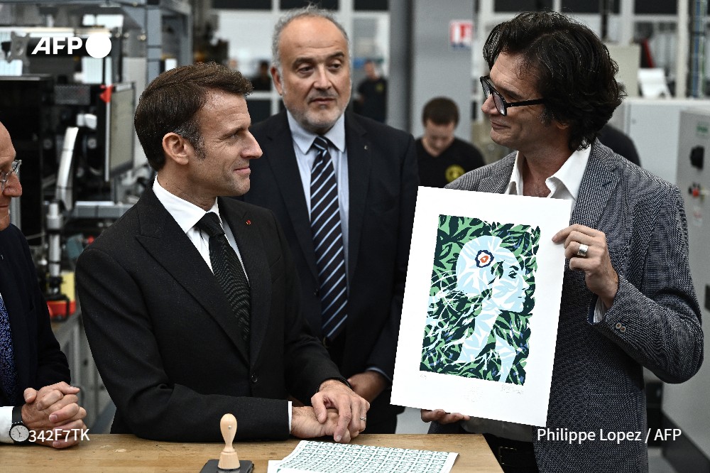 afpfr's tweet image. Emmanuel Macron a dévoilé à l&apos;imprimerie de La Poste de Boulazac (Dordogne) le visage de la nouvelle Marianne - réalisée par le graphiste Olivier Balez - symbolisant la transition écologique, qui va orner les timbres d&apos;usage courant à partir du 13 novembre prochain #AFP