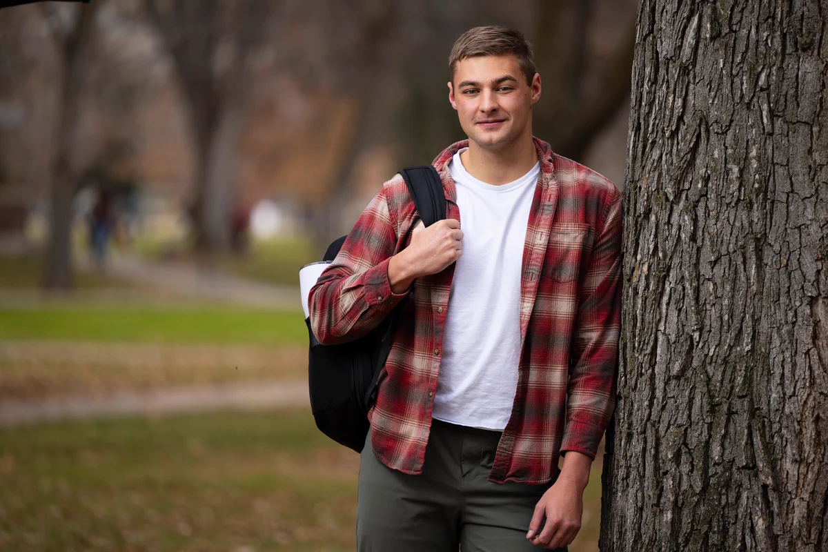 Kolter Stevenson, a University of Montana senior, leaning against a tree on campus