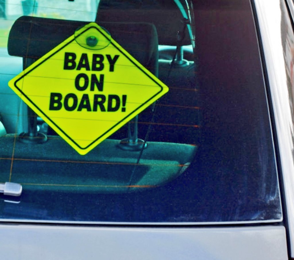 PCPappy's tweet photo. Sign on back says baby on board. Should have said "3 year old walking around inside the car jumping from front seat to back seat while parents laughed. 
They weren’t laughing after the ticket. 
On the wet 401 express hwy no less!
$240, 2 demerit points
#TrafficSafety #VisionZero https://t.co/YFTqjmLA1F