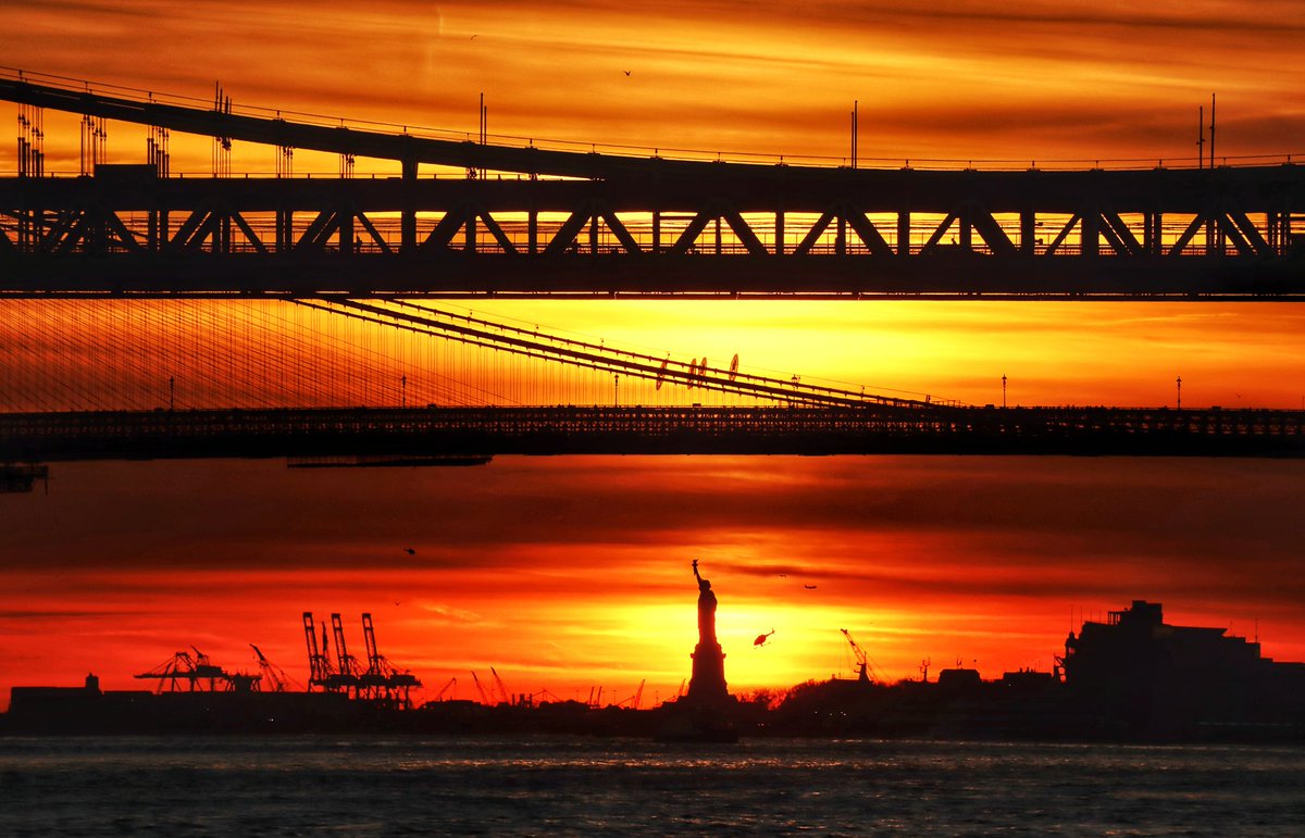 Shades of yellow and orange as the sun sets behind the Statue of Liberty, Brooklyn Bridge and Manhattan Bridge in New York City, Wednesday evening #newyork #newyorkcity #nyc #sunset @statueellisnps #statueofliberty