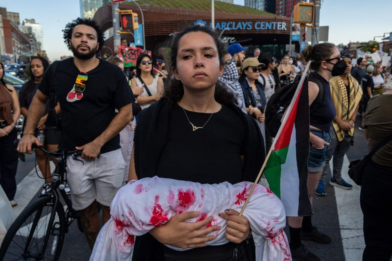 Apastmoment's tweet photo. @Byoussef A woman holds a bloody shroud as people take part in a protest in support of the Palestinian people in New York https://t.co/HoG24c9Xjc