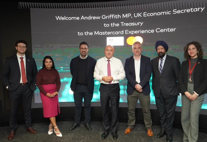 The Economic Secretary stands alongside business leaders and employees. The background says "Welcome Andrew Griffith MP, UK Economic Secretary to the Treasury to the Mastercard Experience Center