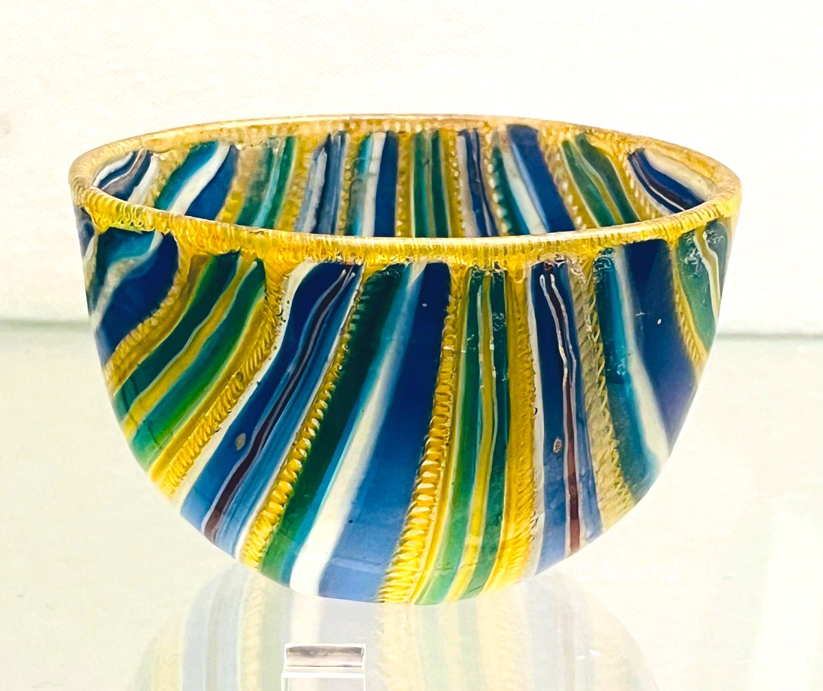 A small jewel-coloured glass cup from Pompeii, perhaps used as a wine cup 2,000 years ago.

Made of ‘ribbon’ mosaic glass, this lovely object beautifully showcases the skill of ancient glassworkers.

Museo Archeologico Nazionale di Napoli. My photo 2023.

#Archaeology