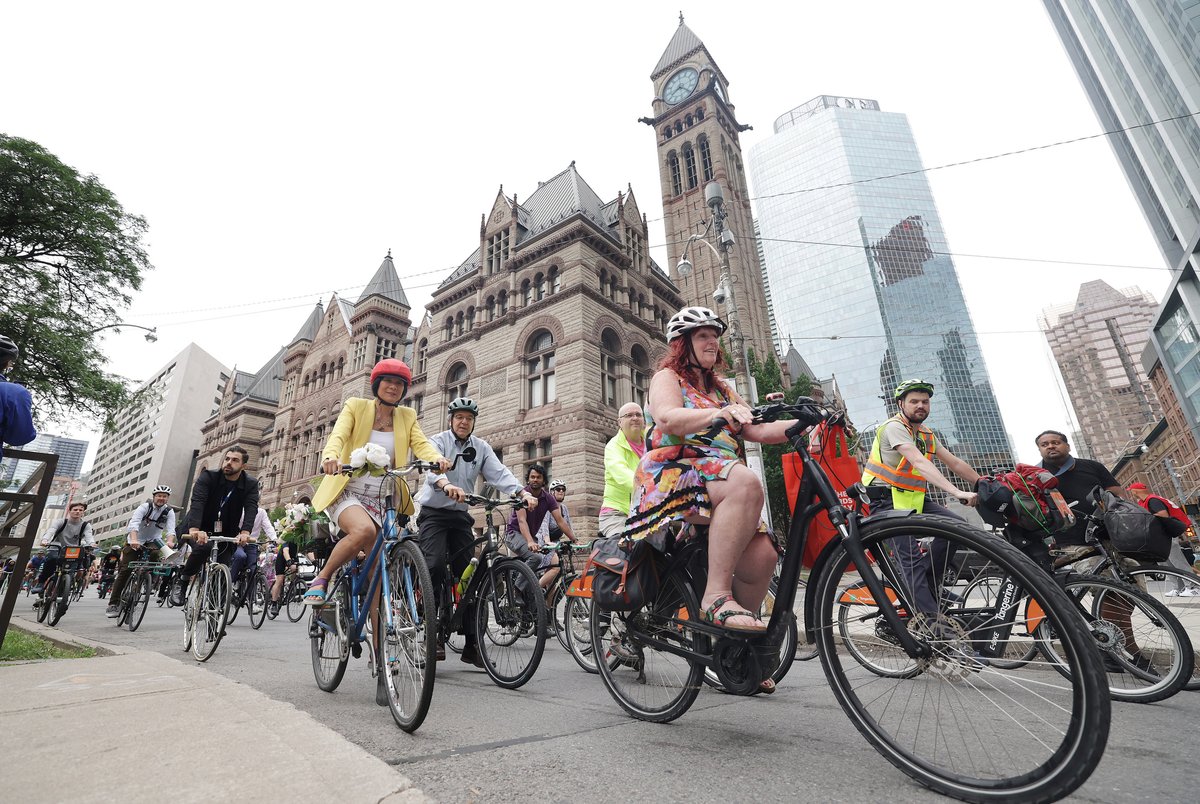 SteveRussell's tweet photo. Mayor-elect Olivia Chow rides with a peloton of supporters down Bay Street to Nathan Phillips Square in front of City Hall on the day she takes the declaration of office in Toronto. #TOpoli #ONpoli https://t.co/ksI2cfQRLp