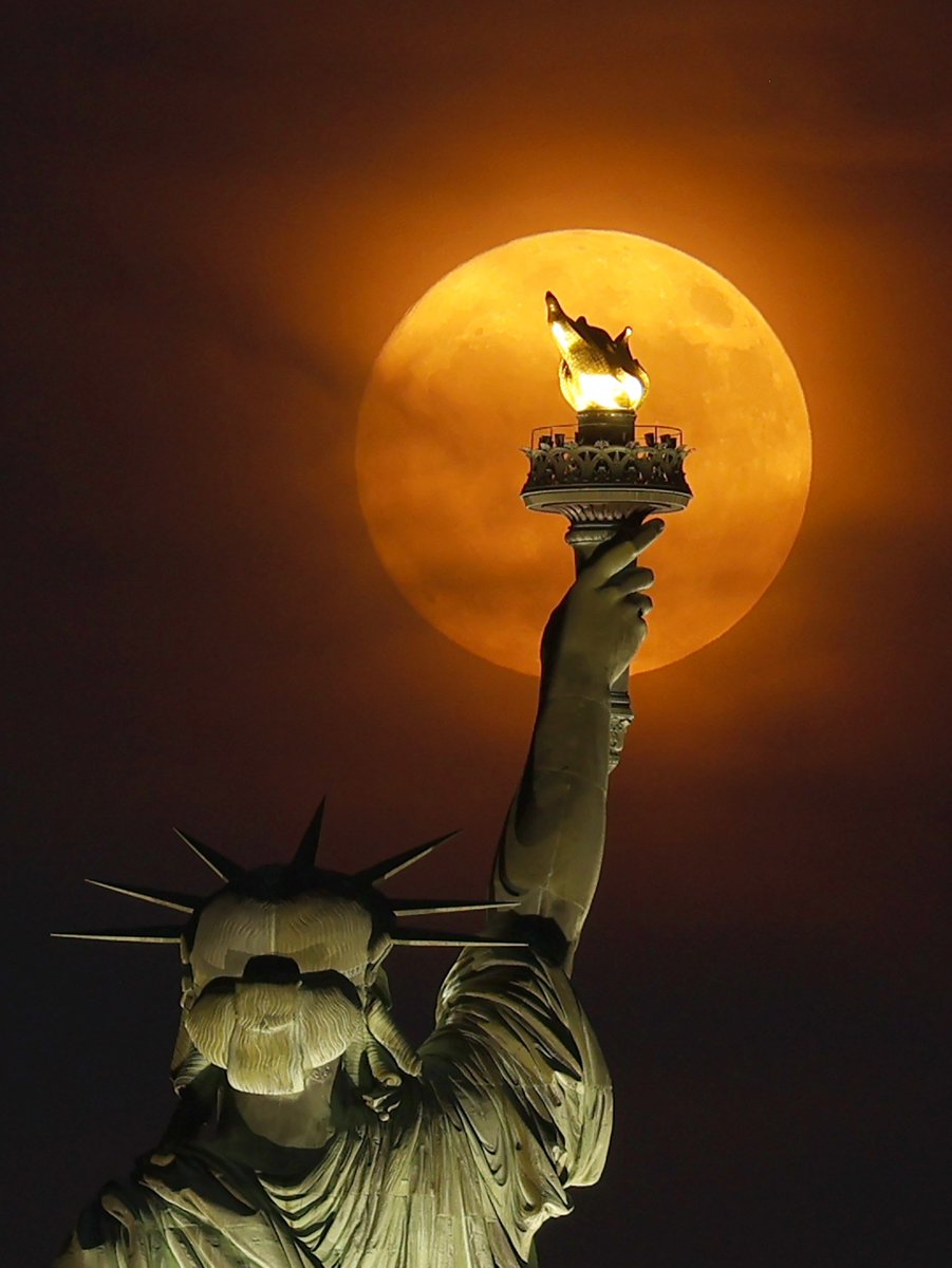 GaryHershorn's tweet photo. The Buck Moon rising through a haze  behind the Statue of Liberty in New York City, Sunday evening #newyork #newyorkcity #nyc @statueellisnps #statueofliberty #moon #BuckMoon @agreatbigcity https://t.co/6VTyjuRPpF