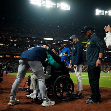 Bryan Woo leans down to hug his grandfather, in a wheelchair, surrounded by family on the field at Oracle Park.