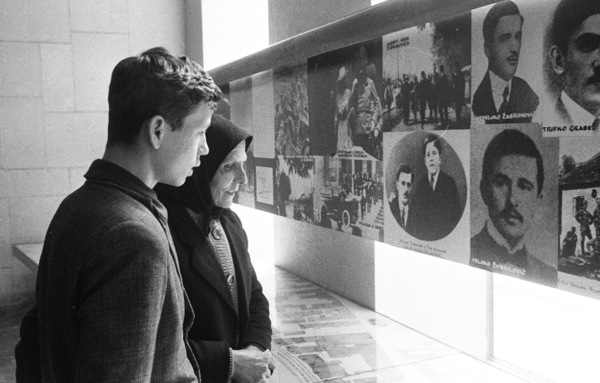 infinite_milos's tweet photo. An unknown old lady tells something to a young boy (probably her grandson). 

They are looking at the documents and photos of the assassination. 

He might be around 70 now. 

The importance of the assassination and the memory of it are pretty much still with us. https://t.co/lnf6Z4WCL6
