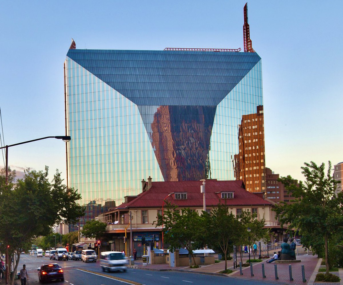 Askash's tweet photo. Do you recognise this Diamond in Diagonal Street, Johannesburg?💎

💎 Floors: 20
💎 Height: 80m
💎 Cost: R65 million
💎 Architect: Helmut Jahn
💎 Built: 1983 and opened: 1984
💎 GLA (gross lettable area): 37 758.24m2
💎 Location: 11 Diagonal Street, #Johannesburg CBD
💎 Tenants over the years include: Absa, Anglo American, De Beers, Sunday Times Newspaper and more recently; Department of Development Planning and Local Government

The building is known as the Diamond building due to its shape and shiny facade with angles in such a way that it represents a multi-faceted diamond. It was designed like this so that every other building surrounding it would shine onto its facade - making every other building the real star when it comes to this cleverly positioned diamond. 

Quite amazing to think that this building was built in the 80’s. If I showed you an image of this building with no context, many would think it was built more recently because of its modern design. This architecture is longevity at its finest. The architect himself is well-known for his brilliance. He designed the Sony Centre in Berlin as well as an airport in Bangkok, Thailand. 

Got any memories connected with this building? Please do share below.