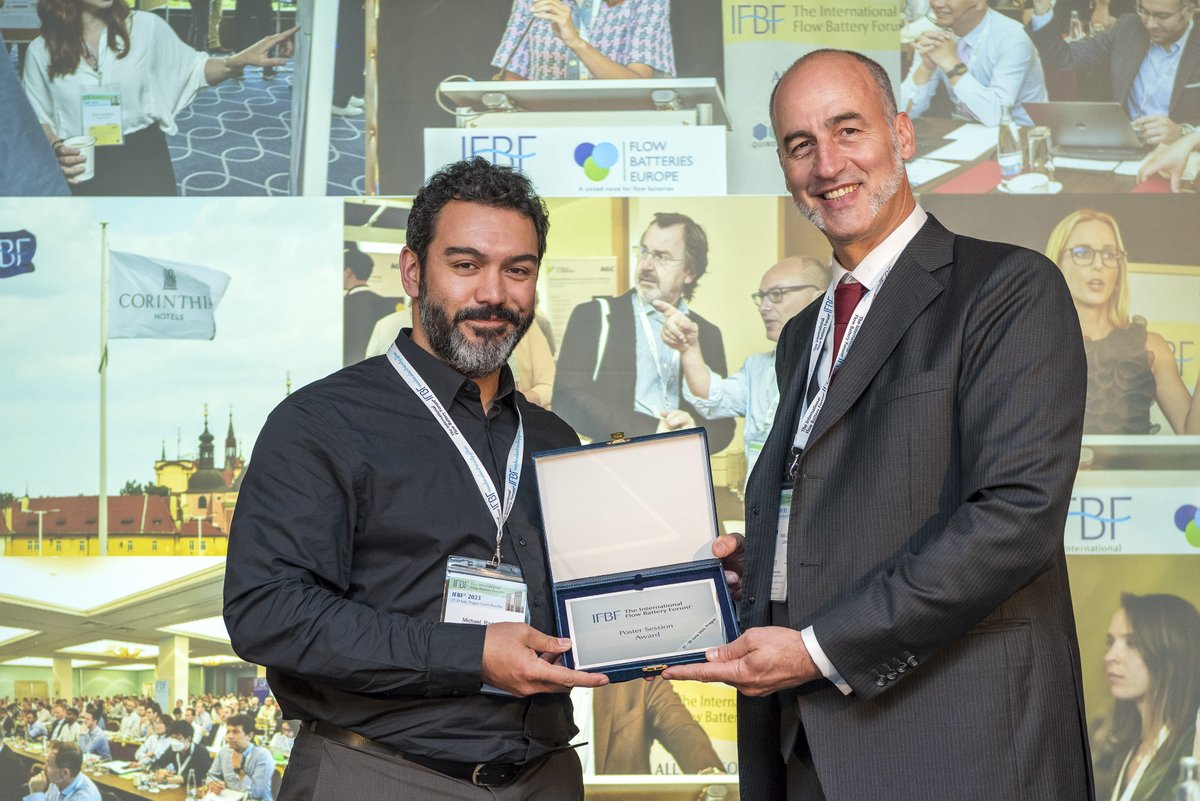 Gratulation an unseren Redox-Flow-Spezialisten Michael Radspieler (links), der kürzlich  den Posterpreis (Mitte) des <a href="/IFBFFlowBattery/">IFBF - International Flow Battery Forum</a> 2023 in Prag (Hintergrund) gewann. Das prämierte Poster: flowbatteryforum.com/wp-content/upl…