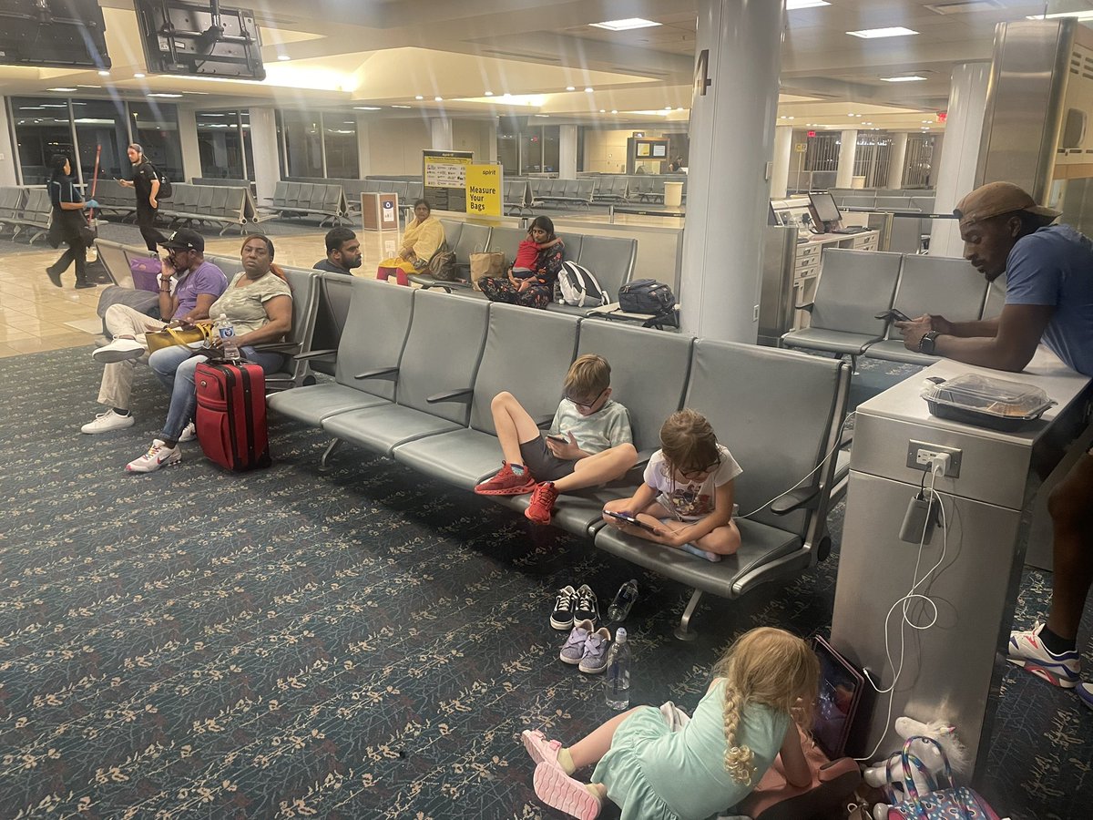 allison____mil's tweet photo. This is @SpiritAirlines standard of service. 3 families spending the night in a disgusting airport with no bedding to sleep on, no basic toiletries offered or provided and no food or drink available. There are 4 small children forced to sleep on a filthy floor or filthy chairs. https://t.co/6kVN68WdTM