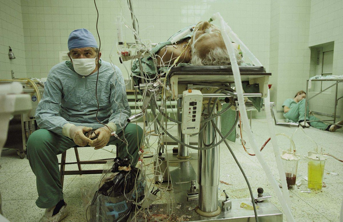 Dr. Zbigniew Religa, a Polish doctor, anxiously watched a screen to check his patient's response after a heart transplant. The surgery was complex and lasted 23 hours. In the photo, you can see one of his colleagues who helped him with the operation asleep in the corner.

Dr.