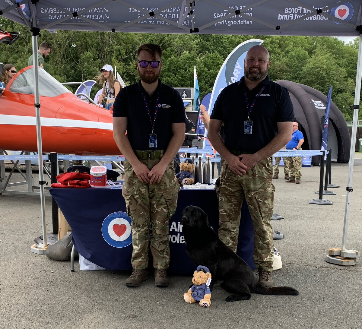 RAFBF's tweet photo. Just had a special visitor. This is Ted, he’s keeping us safe this weekend. He made a new friend on our stand who is now going round Silverstone with him. Pictured with our lovely helpers, Joe and Richie. #RAFBF1 #BritishGP https://t.co/m7bZdrWcXV