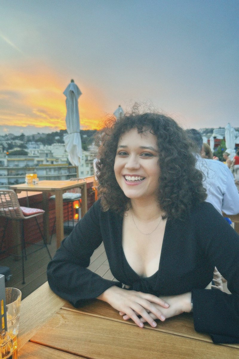 Chante is sat at a table, with a yellow sunset in the background.