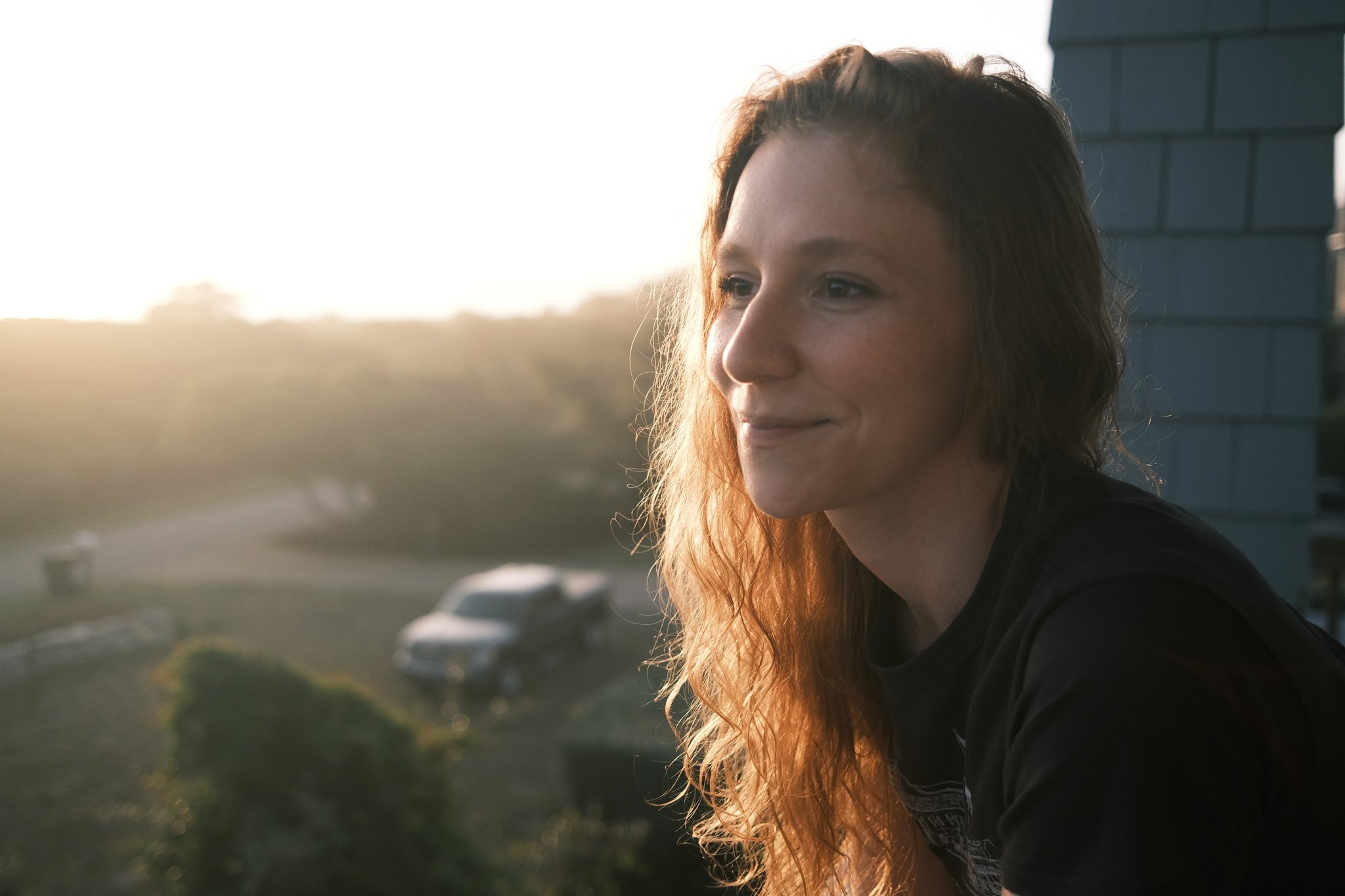 abigail wahl, a woman with strawberry blonde hair looks out over a balcony at sunset, smiling