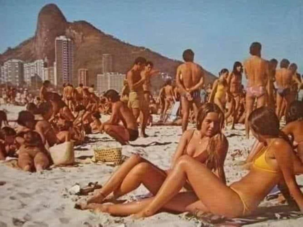 Una Playa en los años 70.
No había los mismos niveles de obesidad.
Sin implantes de plástico y tatuajes.
Sin camisas porque tumbarse en la arena reduce el estrés.
Sin sombrillas porque el sol mejora hasta cierto punto la salud.
Sin gafas de sol. 
Nada de cremas faciales tóxicas .