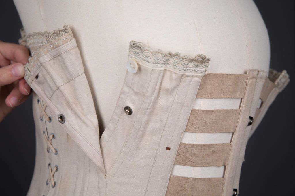 This c. 1910s corset is designed for use during pregnancy and nursing. The side panels seams are laced and can be adjusted to suit a changing body shape. The bust panels can be opened with both a metal popper and bone button, offering convenience for the wearer to breastfeed.