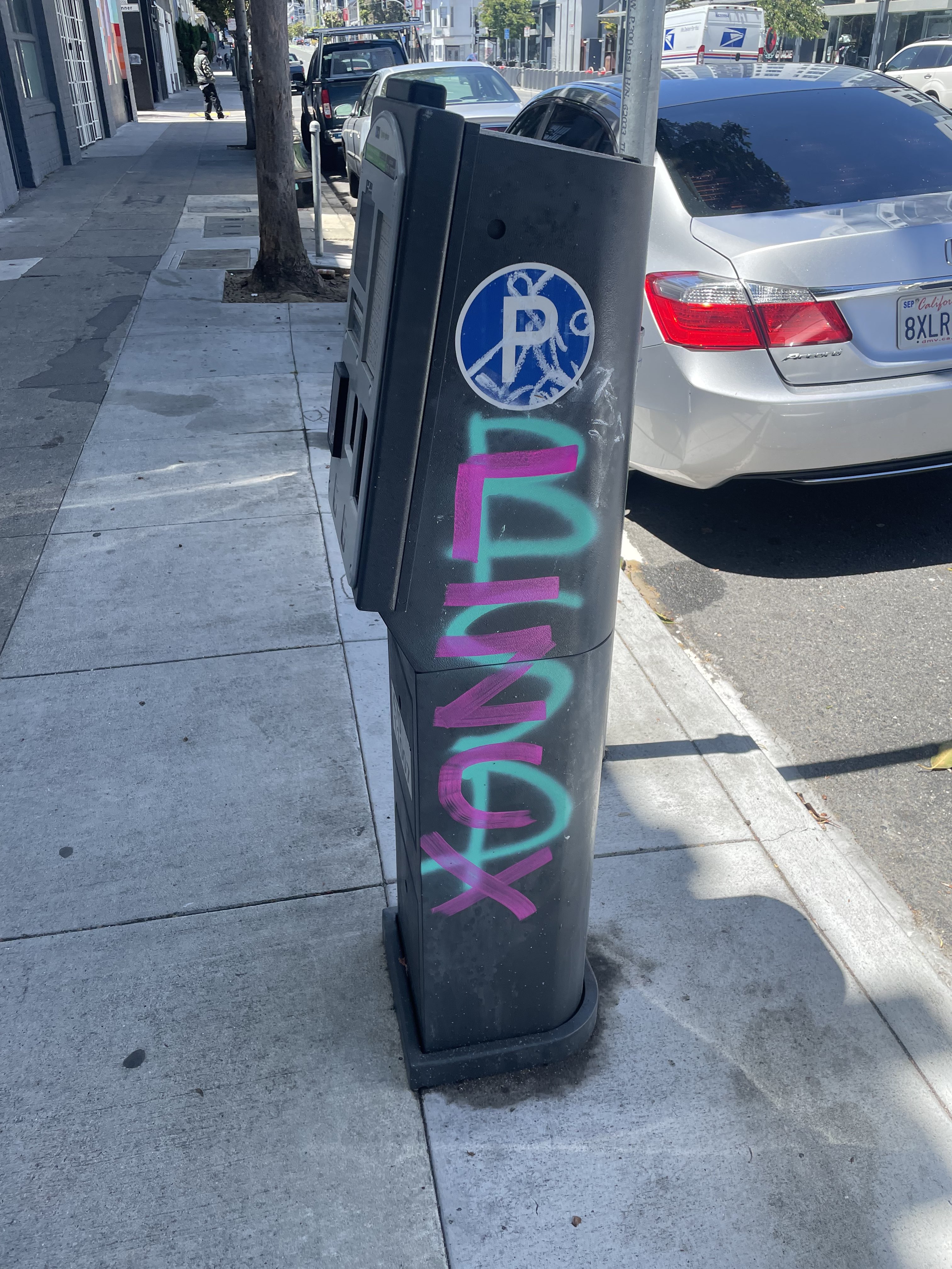a parking meter with the word BSD graffitied on it in teal, and LINUX over that, in purple