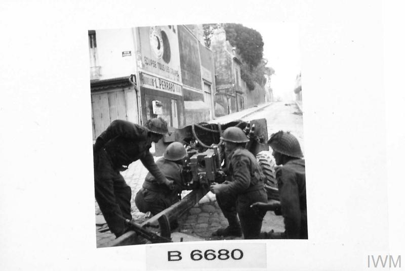 BattlefieldBen's tweet photo. #OTD #OpCharnwood #normandy23 

9 July

An anti tank gun, 6 pdr, and crew setup looking eastwards in Caen centre.

The realities here are this would have been staged. By this time the German forces had fallen back to the southern half of Caen. Not visible in this photograph, the rumble blocking the streets would have stopped most advances by armour in the centre area towards the allied approaches.

This is men of the British 3rd Infantry Division.