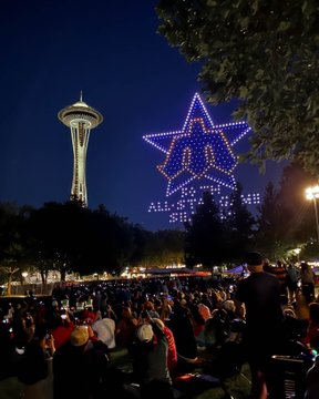 Drones light up the sky next to the Space Needle in the shape of the 1979 All-Star Game logo.