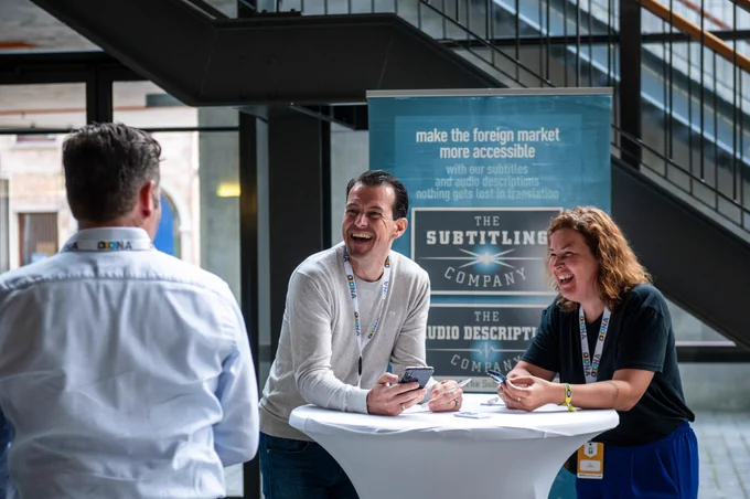 Participants talking and laughing at the booth of The Subtitling Company