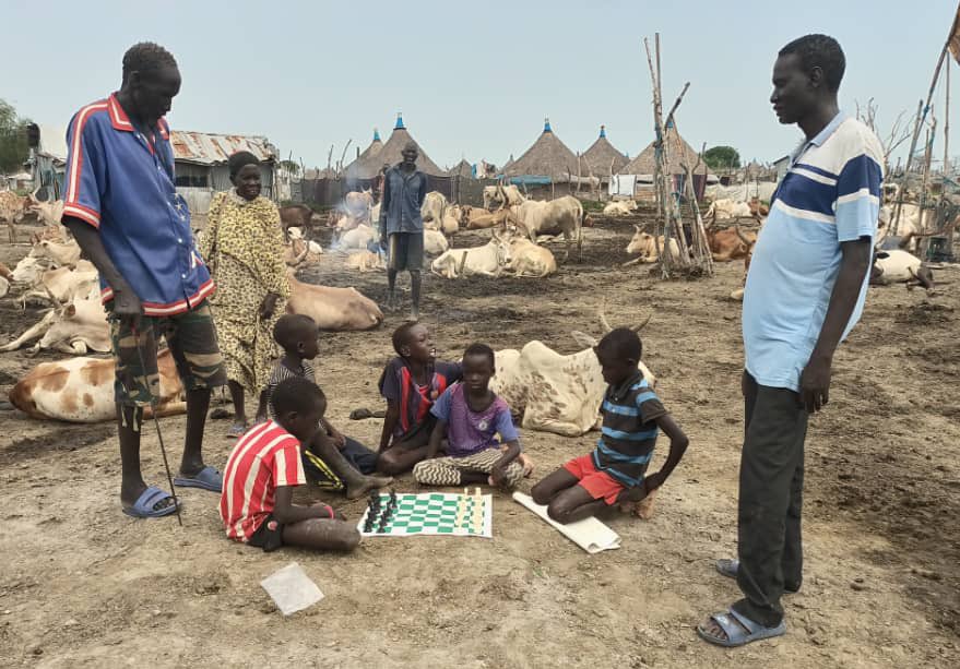 Children play a game of chess within a cattle camp in South Sudan.