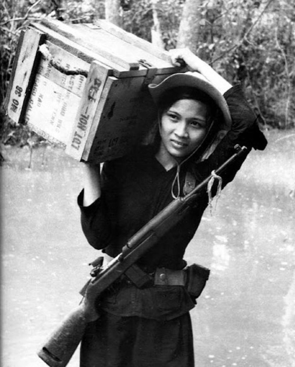 historyinmemes's tweet photo. During the Vietnam War the Ho Chi Minh trail played a crucial role in supplying the communist forces in South Vietnam from North Vietnam. The trail was a network of paths and routes that spanned across the neighboring countries of Laos and Cambodia, providing a strategic supply route for the Viet Cong and the North Vietnamese Army, also known as the Viet Minh.

The Viet Minh, led by Ho Chi Minh, consisted of a diverse group of soldiers, including women who actively participated in the war effort. In this photograph, a female soldier from the Viet Minh is depicted carrying a box of supplies on the Ho Chi Minh trail. These supplies would have been essential for supporting the communist forces in the south, providing them with ammunition, food, medical aid, and other necessities.

The trail itself was a challenging and dangerous route, passing through rugged and heavily forested areas. It was constantly targeted by American forces through aerial bombings and ground attacks in an attempt to disrupt the flow of supplies. Despite these risks, the Viet Minh soldiers, including women, showed great determination and resilience as they transported vital provisions along the trail, navigating difficult terrain and evading enemy detection.

The Ho Chi Minh trail became a symbol of the resourcefulness and determination of the Viet Minh and their unwavering commitment to the communist cause. It played a significant role in sustaining the war effort and enabled the communist forces to continue their resistance against the American-backed South Vietnamese government. The efforts of the female soldier in transporting supplies underscore the important role that women played in the Vietnam War, both in combat and in supporting logistical operations.