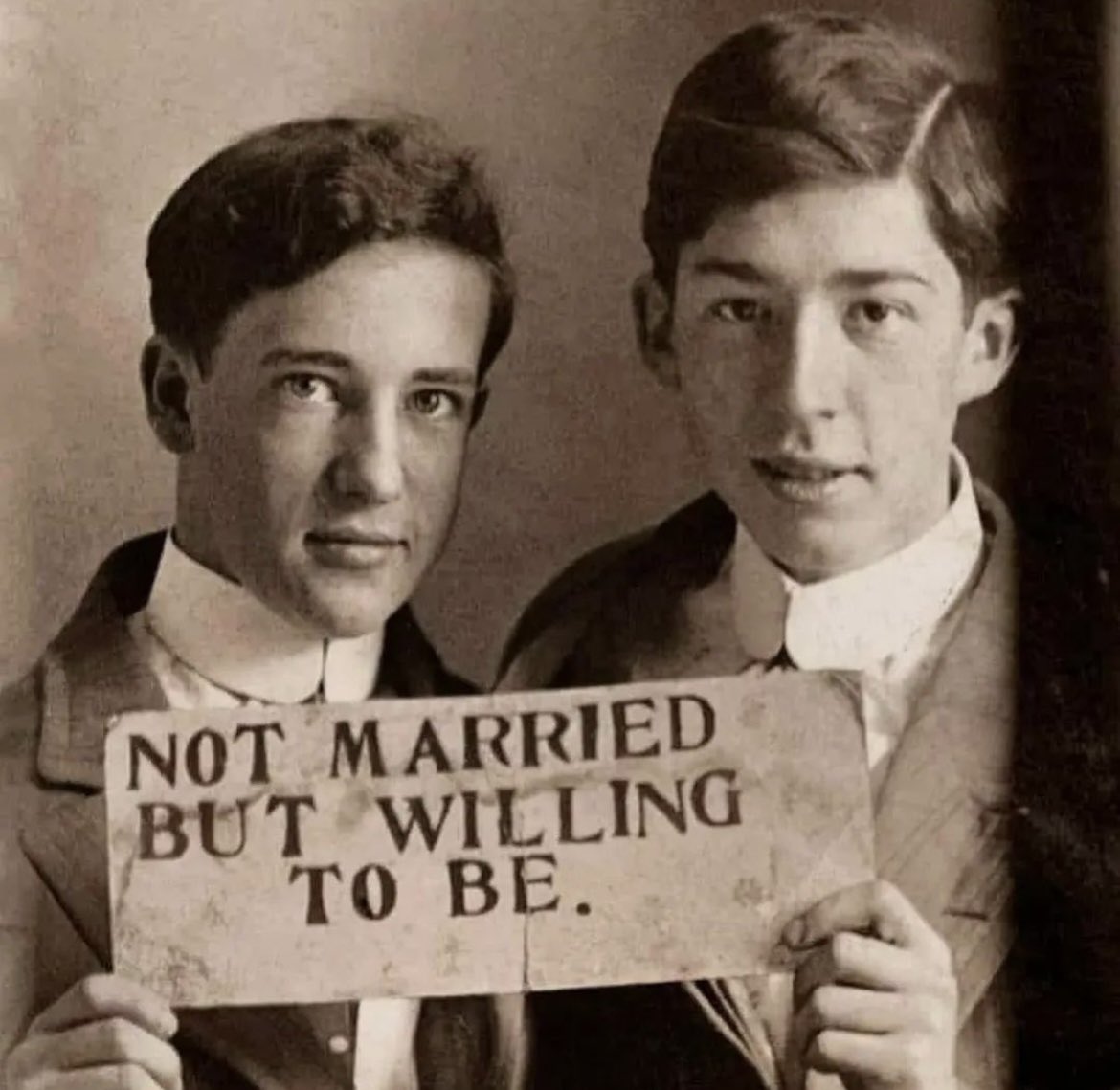 Two young men hold a pre-printed sign, approximately 120 years ago, proclaiming their bond and willingness to be legally wed to one another.