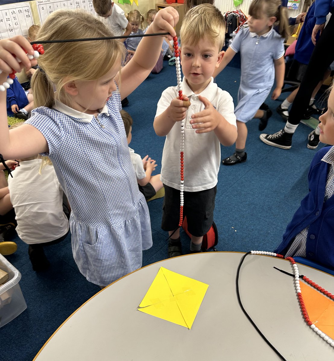 Reception children using the bead string to find out how many beads are needed to fit around the shapes made from the four triangles task.  Counting in tens and telling me the units is beads. <a href="/helenjwc/">Dr Helen J Williams she/her🇪🇺</a> <a href="/DrHelenDrury/">Helen Drury</a> <a href="/BPSHead/">BPSnews💙</a> <a href="/BPSEYFS/">BPSEYFS</a>