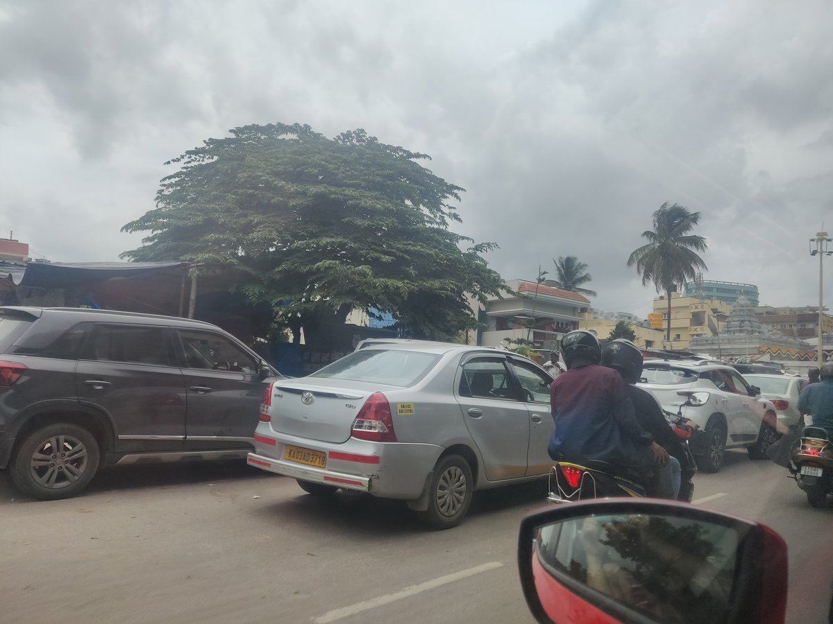 zooniberi's tweet photo. @blrcitytraffic cars parked on the road with pandal and functions happening outside on the road. No police to mitigate traffic with vehicles travelling wrong way and double lanes of cars parked on the Bellary main road near GKVK gate bus stop. Please note. https://t.co/pMiUiu5TrY
