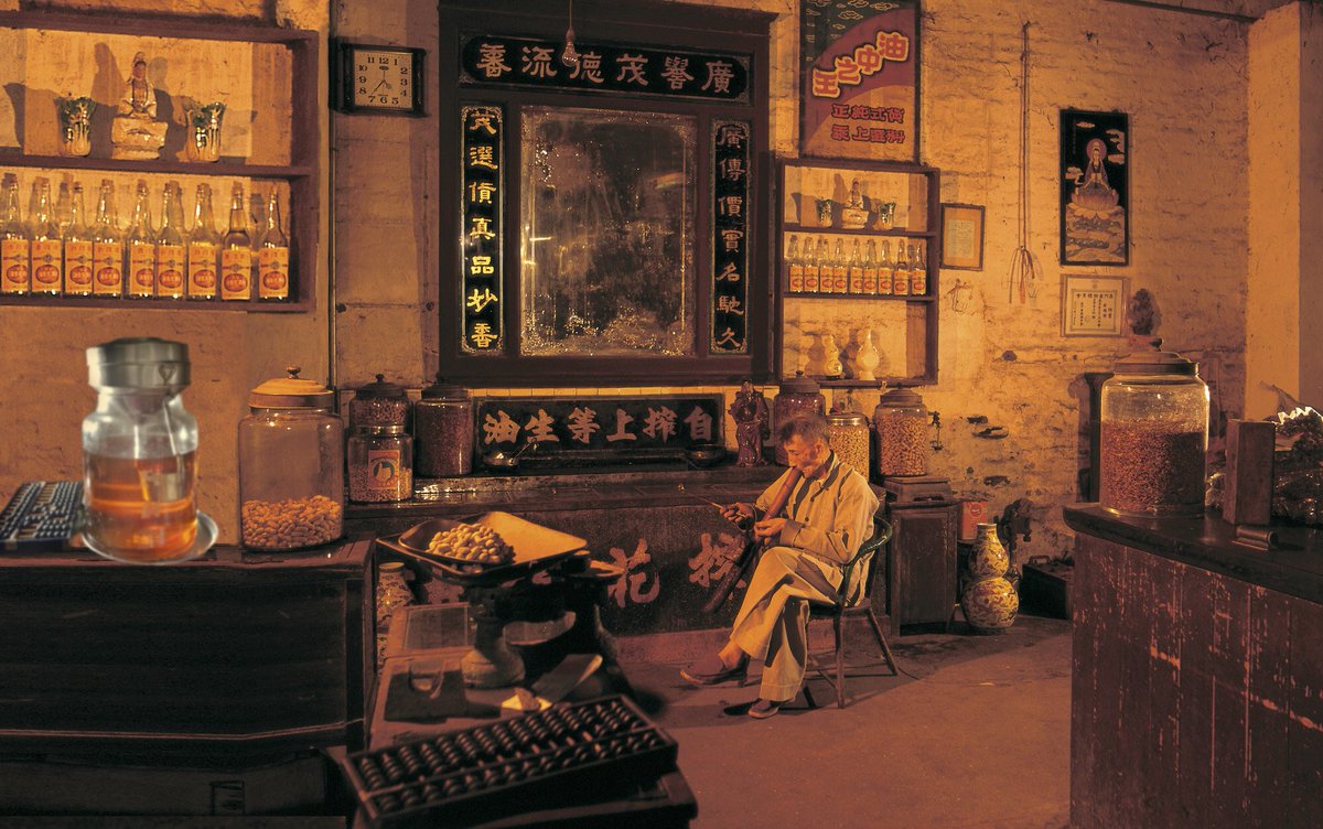 A shop owner enjoys a pipe of tobacco in a traditional Chinese store, Hong Kong, 1970s. 
Photo by Frank Fischbeck.