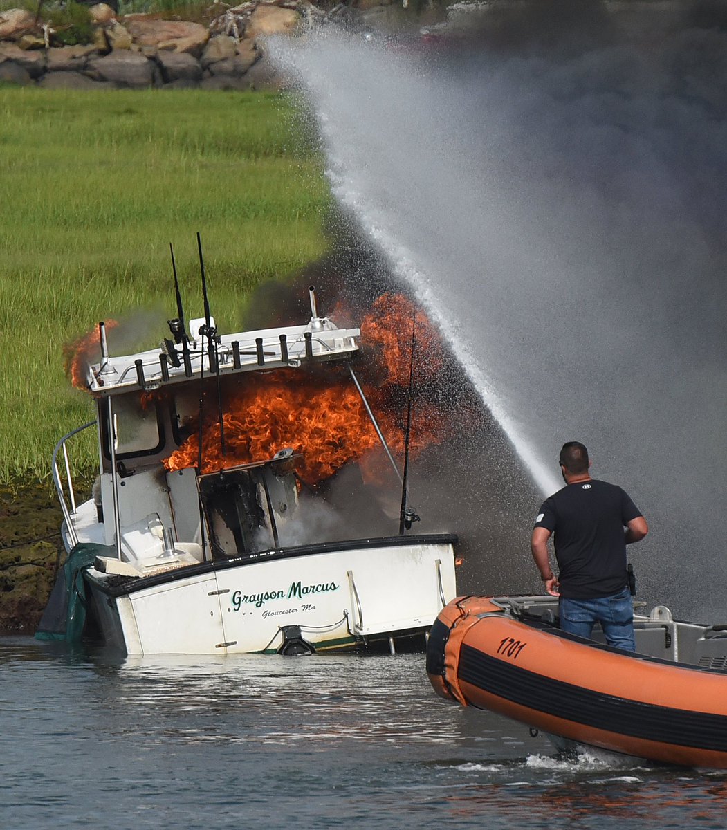 PHBPHOTO's tweet photo. Firefighters and Police use and foam to extinguish a boat fire in the Blynman Canal in Gloucester after it exploded sending two people into the water along with a dog, which was rescued by a boater. @GDTnews https://t.co/O5YqnUJheB