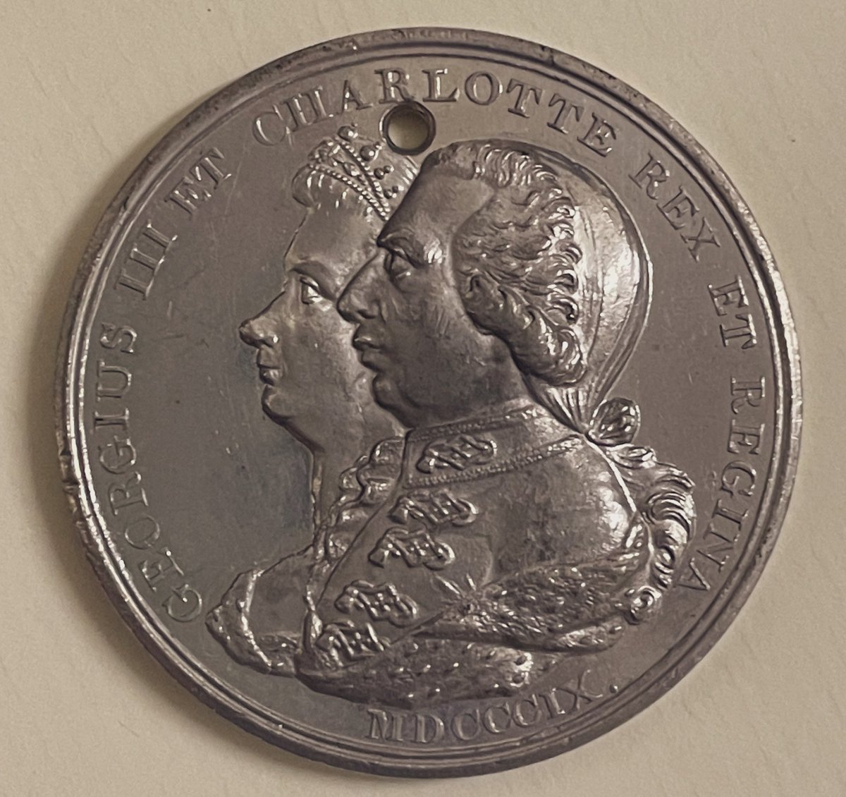Fans of #QueenCharlotte #Bridgerton might enjoy this silver medal made 1809 to celebrate &amp; commemorate the accession of George III. It includes a joint portrait of George &amp; his queen Charlotte, and has a hole pierced in the top, maybe once worn from a ribbon or chain.