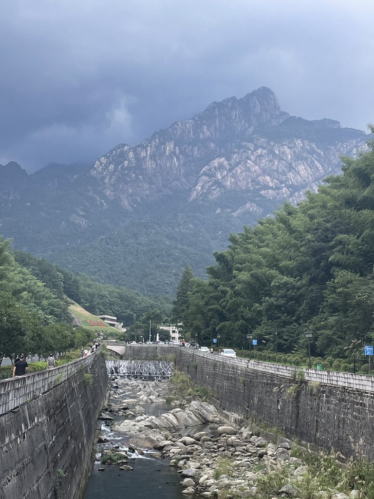 Behold the majestic peaks in the distance, the awe-inspiring foothills of Huangshan. Join me in conquering this grand challenge! Together, let's embark on an adventure of a lifetime and conquer the heights of glory. #Huangshan #MountainChallenge #AdventureAwaits