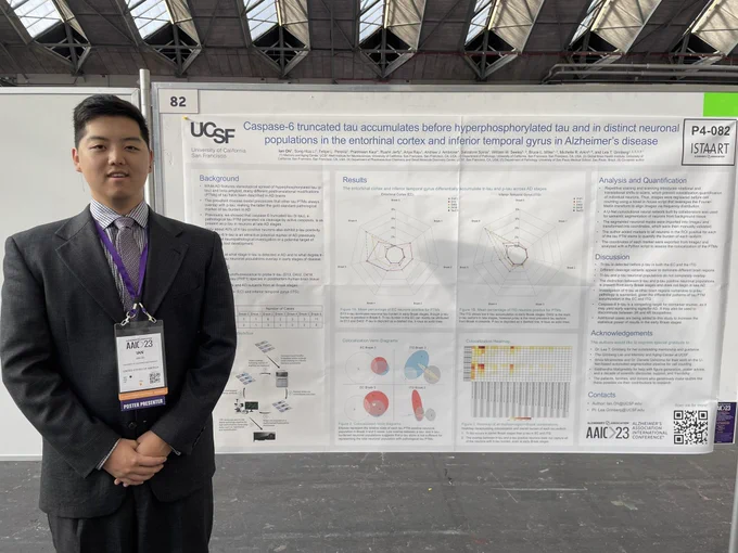 Ian stands in front of his poster, showing differential patterns of tau isoform accumulation across different Braak stages of AD.