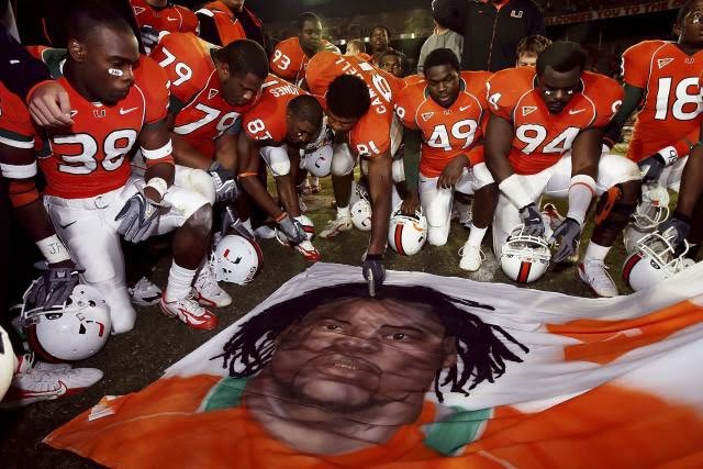 Photo from 2006, showing the Miami Hurricanes gathered at midfield in prayer for their slain teammate, Bryan Pata, who had been gunned down and killed. 15 years later, his teammate, Rashaun Jones (No. 38, at the left), was charged with his murder.