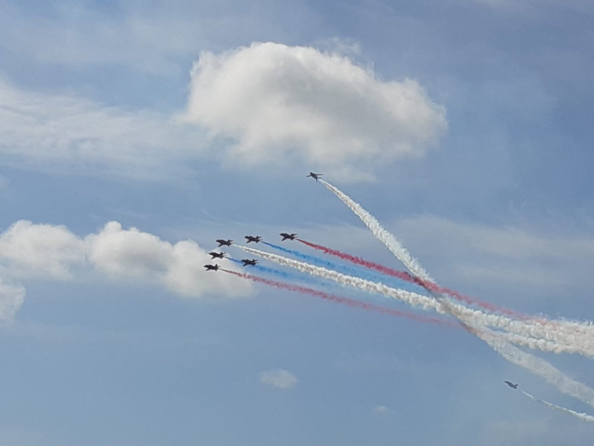 Seven RAF Red Arrows trailed by red, white and blue smoke.