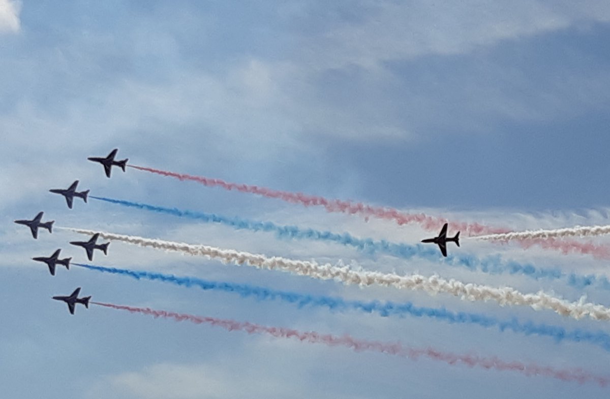 Seven RAF Red Arrows trailed by red, white and blue smoke.