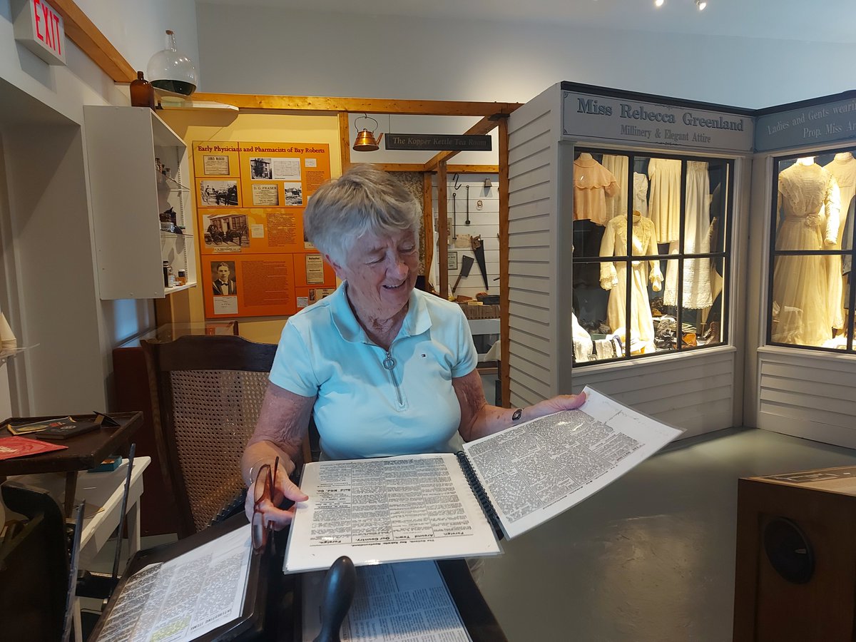 This is H.M. Mosdell's granddaughter reading an issue of the Outlook. The Outlook was a weekly newspaper established at Bay Roberts by H.M. Mosdell in 1903, with the equipment formerly used to print the Vindicator in Brigus.