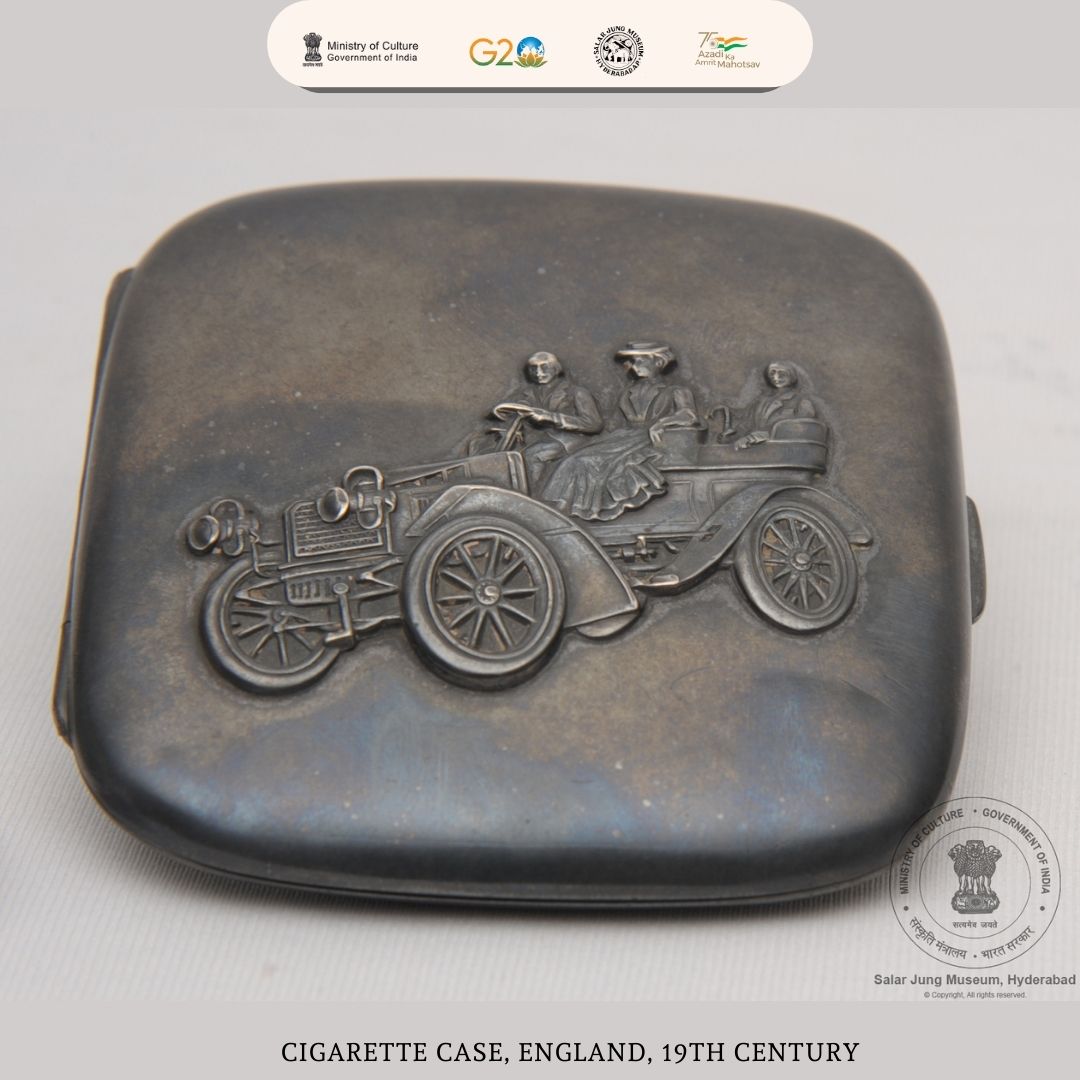 Check out this nickel cigarette case from England dated 19th century. Its lid shows an engraved open motor car with a lady seated next to the driver and a gentleman at the backseat with an umbrella.
#SalarJungMuseum #AmritMahotsav #cigarettecase