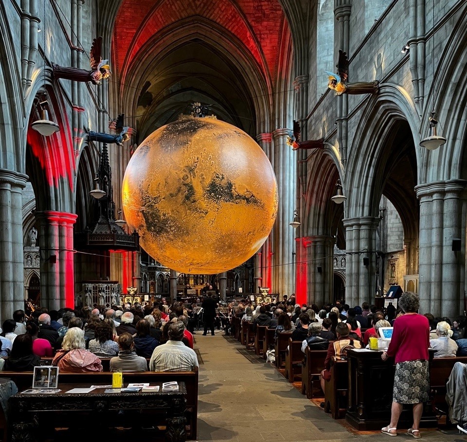kcfestivaluk's tweet photo. What a stunning sold out concert yesterday with @LondonCityPhil conducted by Olsi Qinami performing Holst’s The Planets underneath Luke Jerram's Mars: War &amp; Peace at @StJohnsW14. Book free tickets for further events today @RBKC @RBKClibraries #marsartwork https://t.co/rfKbNkcZCf