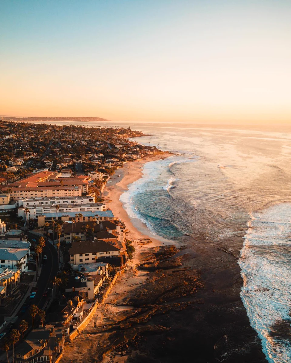 Sunset over the coastline of San Diego with waves crashing against the shore.