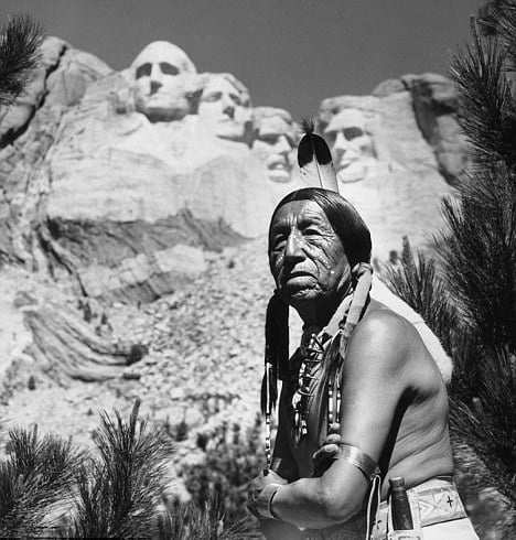Um nativo americano do povo Sioux fotografado em frente ao Monte Rushmore. Dakota do Sul, Estados Unidos, junho de 1957. O monumento com os rostos de quatro presidentes estadunidenses foi esculpido sobre uma montanha sagrada para os indígenas — a Montanha dos Seis Avôs. 1/24