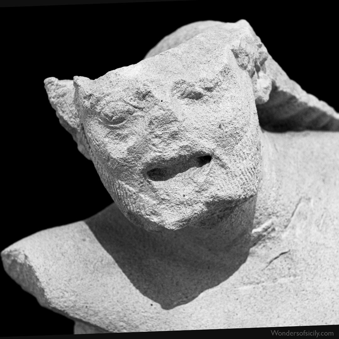 Detail  of a torso portraying an overwhelmed giant with his mouth open in a  grimace of pain. The sculpture was made of Menfi limestone. It was  intended for architectural or votive purposes, according to the  information given by the Archeological Museum in Palermo.