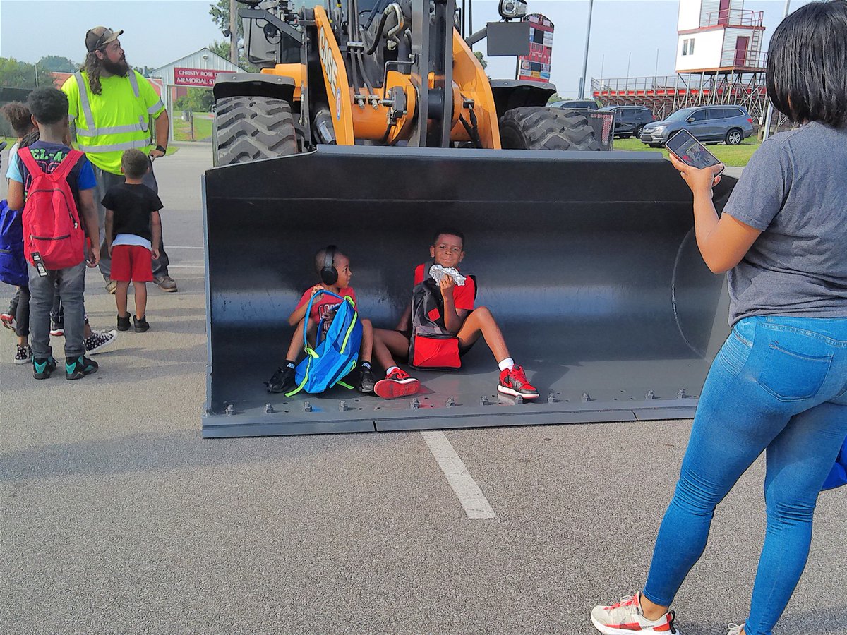 SchoolOfBraam's tweet photo. My fave photo from Fairfield's Back-to-School Bash. Taken by my journalism student Lexi Prince, it encapsulates what went on: Kids, parents, free backpacks/supplies, free food ... and City of Fairfield bulldozers to touch (in which these brothers hunkered down to eat)! #FCSDNews https://t.co/YM9JzIhUzG