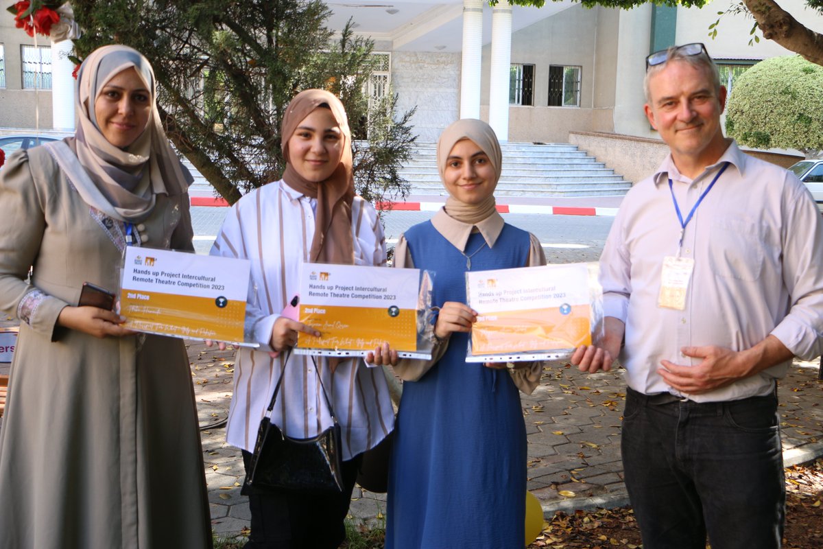 HandsUpProject's tweet photo. Students &amp; teachers in the gardens of the Islamic University, Gaza receive their remote theatre awards &amp;  copies of "Moon Tell Me Truth", the recently published book containing their poems.  @MartinDaltry @eal_teaching @eve_elt @DiverseEd2020 @EduCannotWait @NEUnion https://t.co/VYudQS4eeb