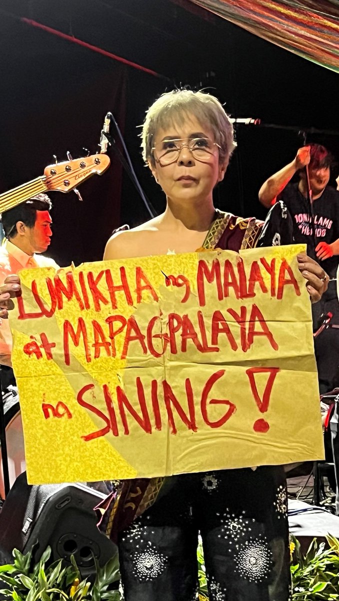 Dolly De Leon holds a sign that says “Lumikha ng malaya at mapagpalaya na sining!” at UP Diliman.