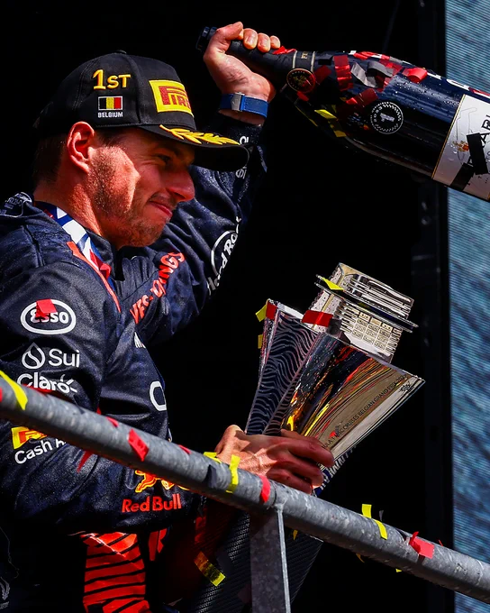 Max Verstappen holds aloft his bottle of sparkling wine and his cruise ship trophy after winning the Belgian Grand Prix.