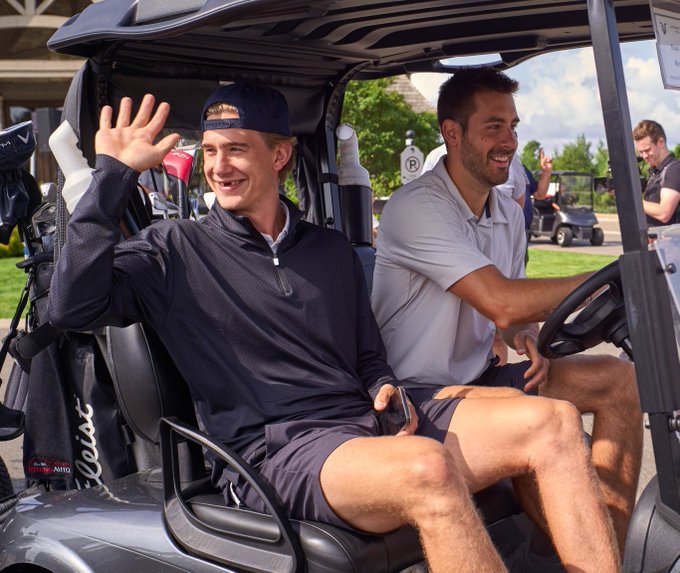 ryan mcleod waving as evan bouchard drives a golf cart