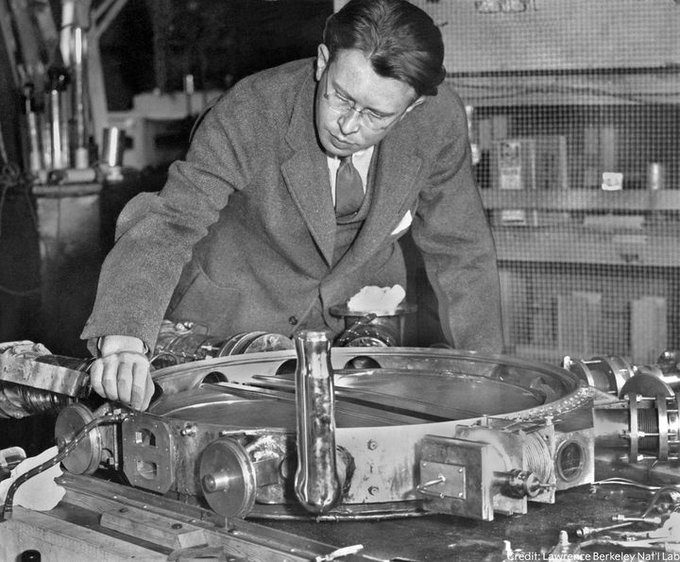 Ernest Lawrence leaning over a 37 1/2-inch vacuum chamber with the lid removed. The photo is in black and white.